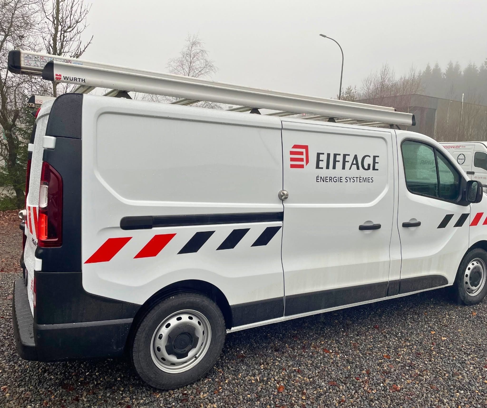 Renault Trafic blanc d'ATI au lettrage Eiffage Énergie Systèmes, bandes rouges et noires, galerie de toit avec porte-échelle