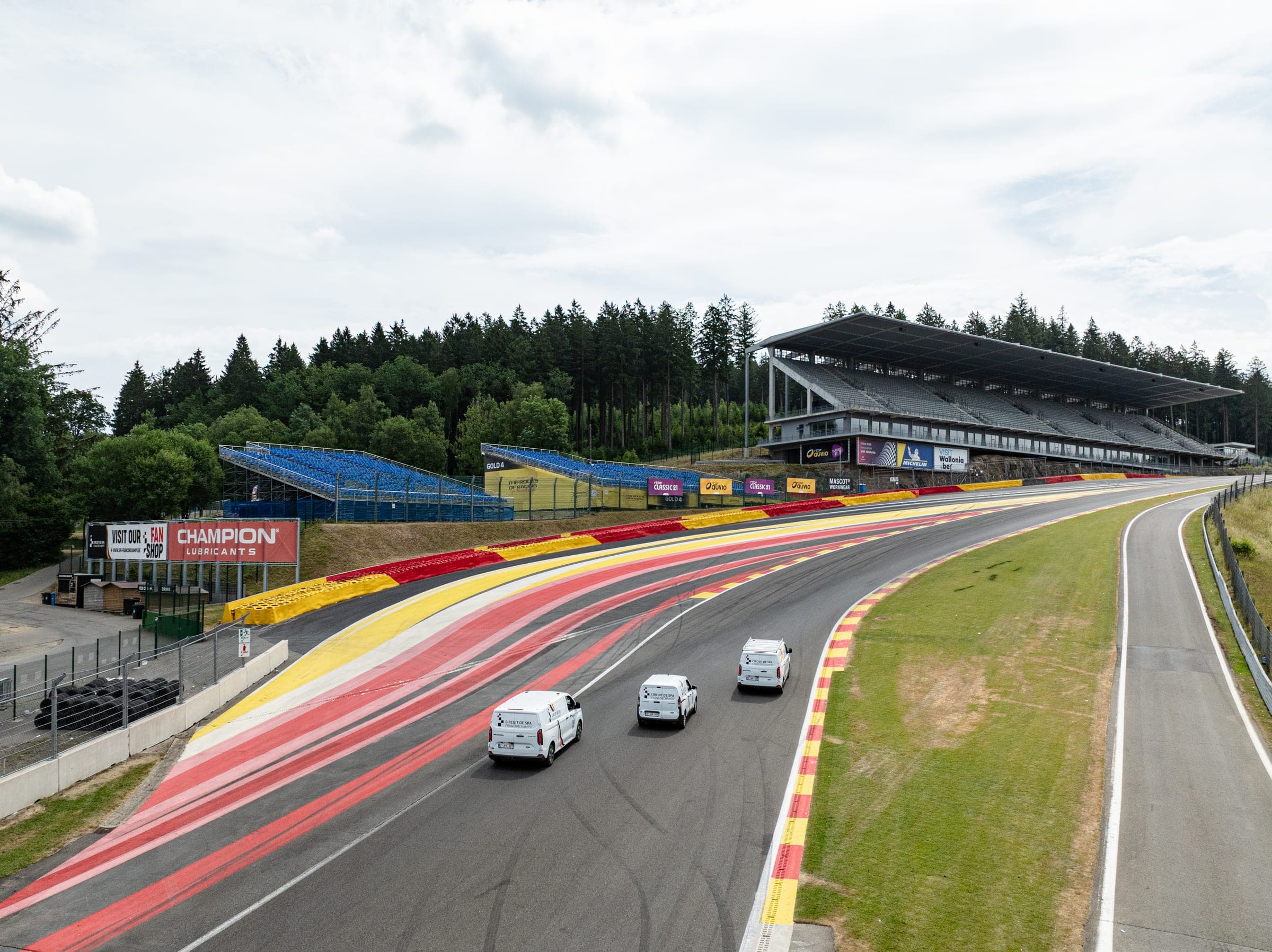 Trois utilitaires aménagés par Amecam devant les tribunes du circuit de Spa-Francorchamps