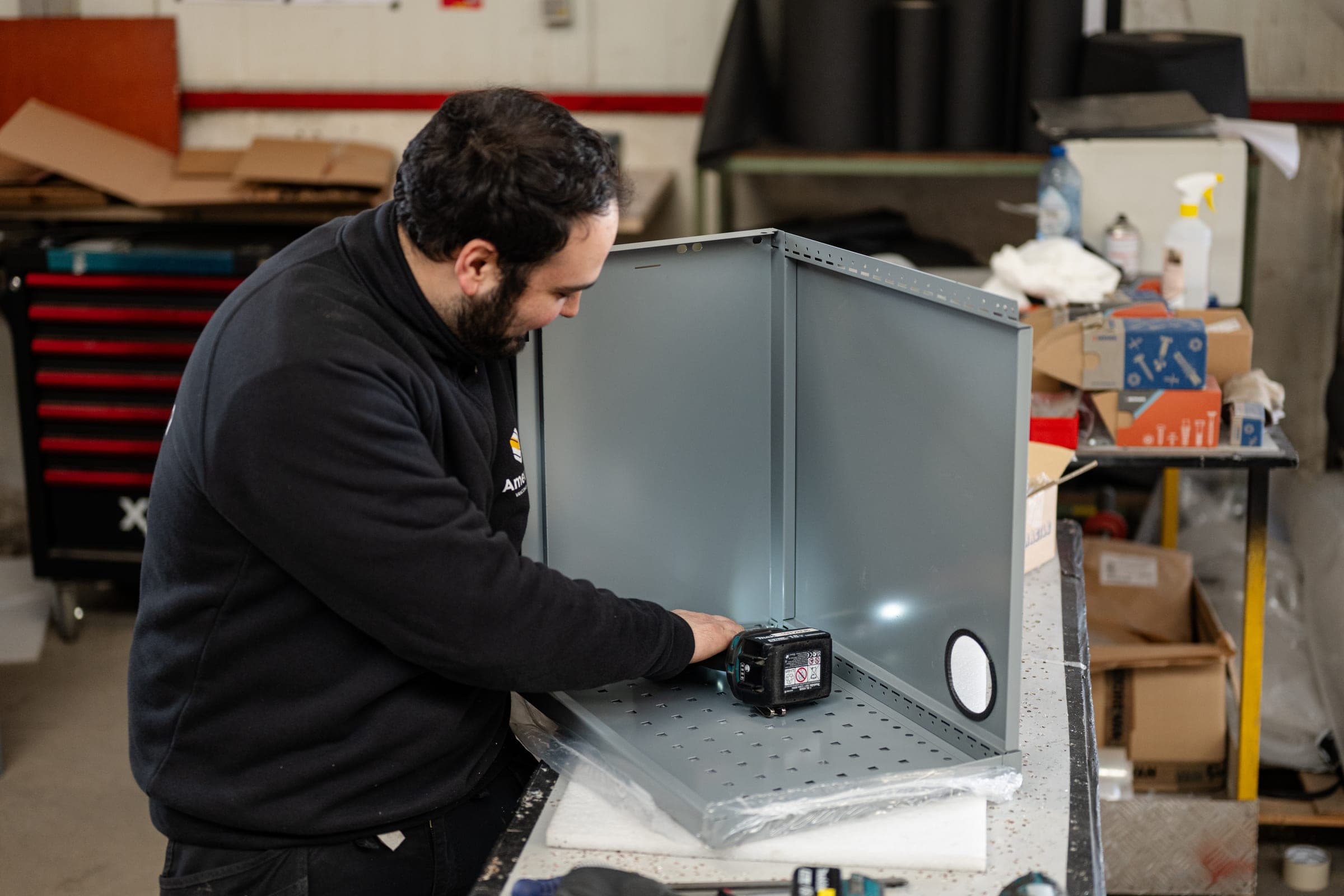 Technicien Amecam assemblant un meuble métallique sur mesure à l’établi de l’atelier