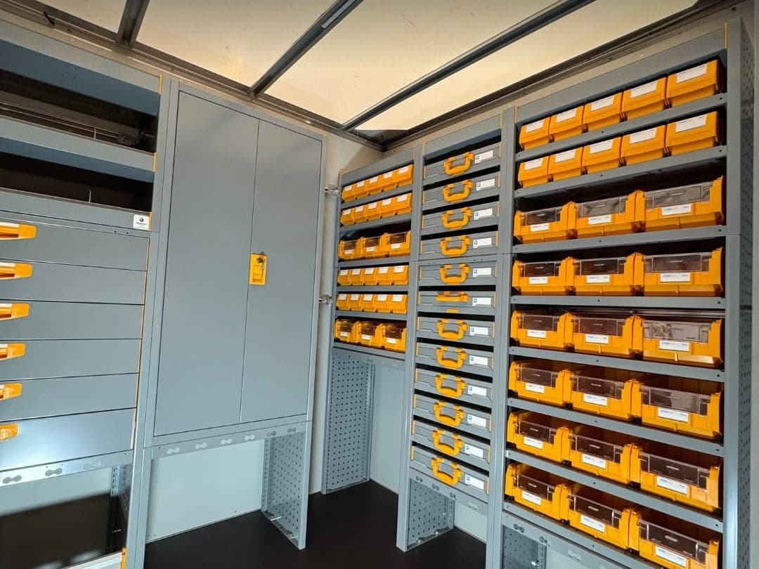 Fond de la caisse avec armoire haute à serrure, colonne de mallettes à poignées orange et casiers à bacs jaunes