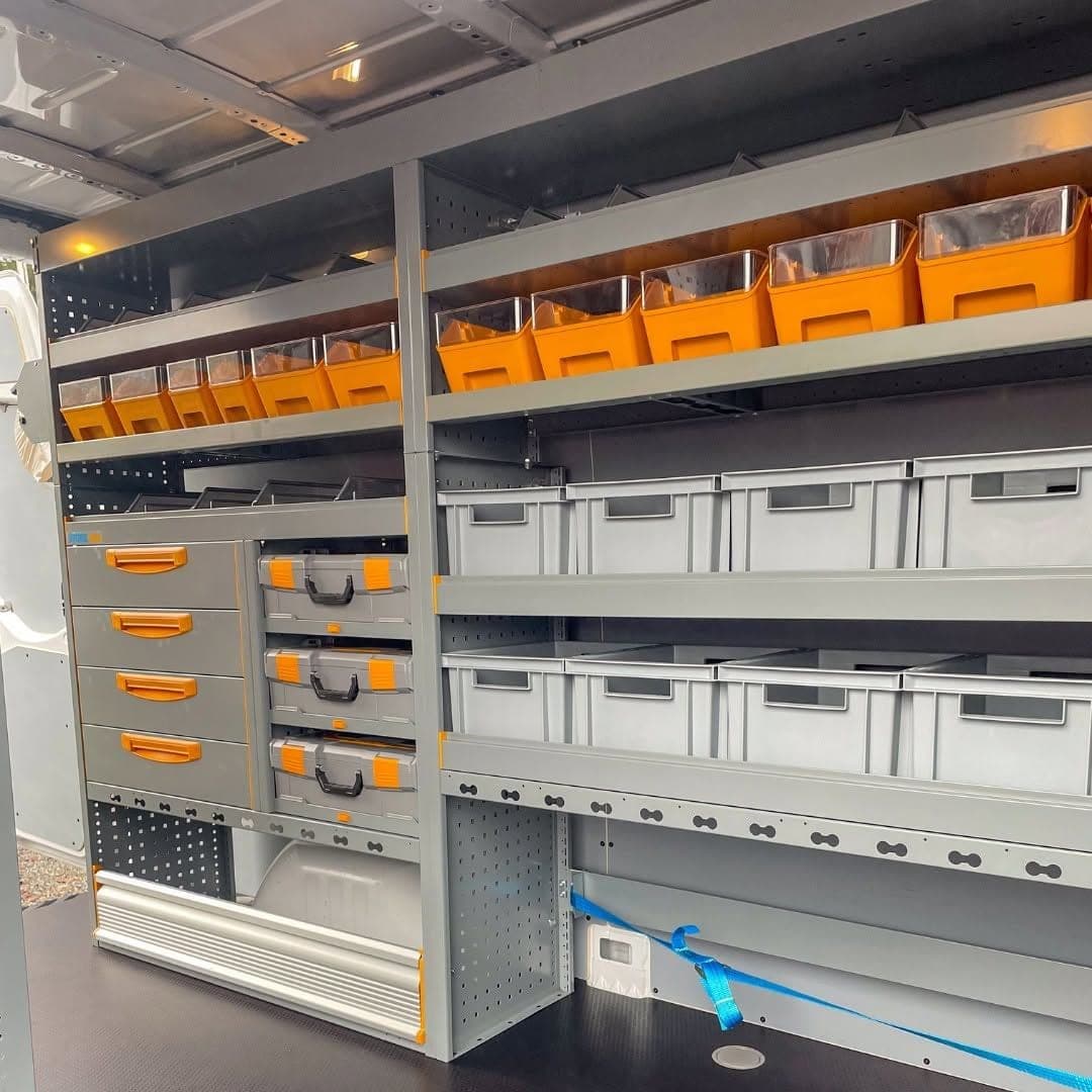 Rayonnage Store Van de Bovy Chauffage, bloc de tiroirs à poignées orange, coffrets de rangement, caisses grises et bacs orange