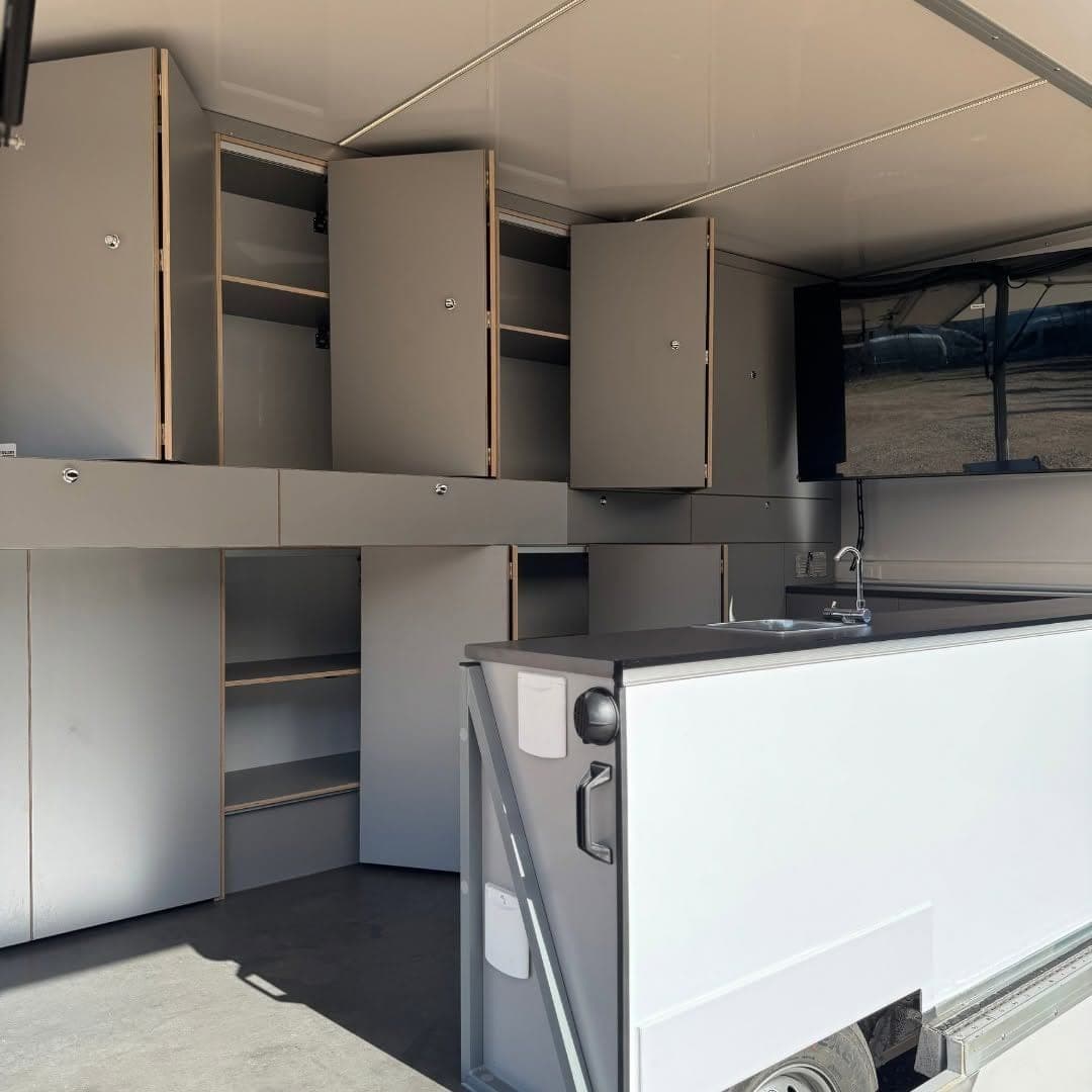 Intérieur du showroom mobile du Parc naturel Hautes Fagnes-Eifel, armoires grises ouvertes, étagères, comptoir avec évier et écran