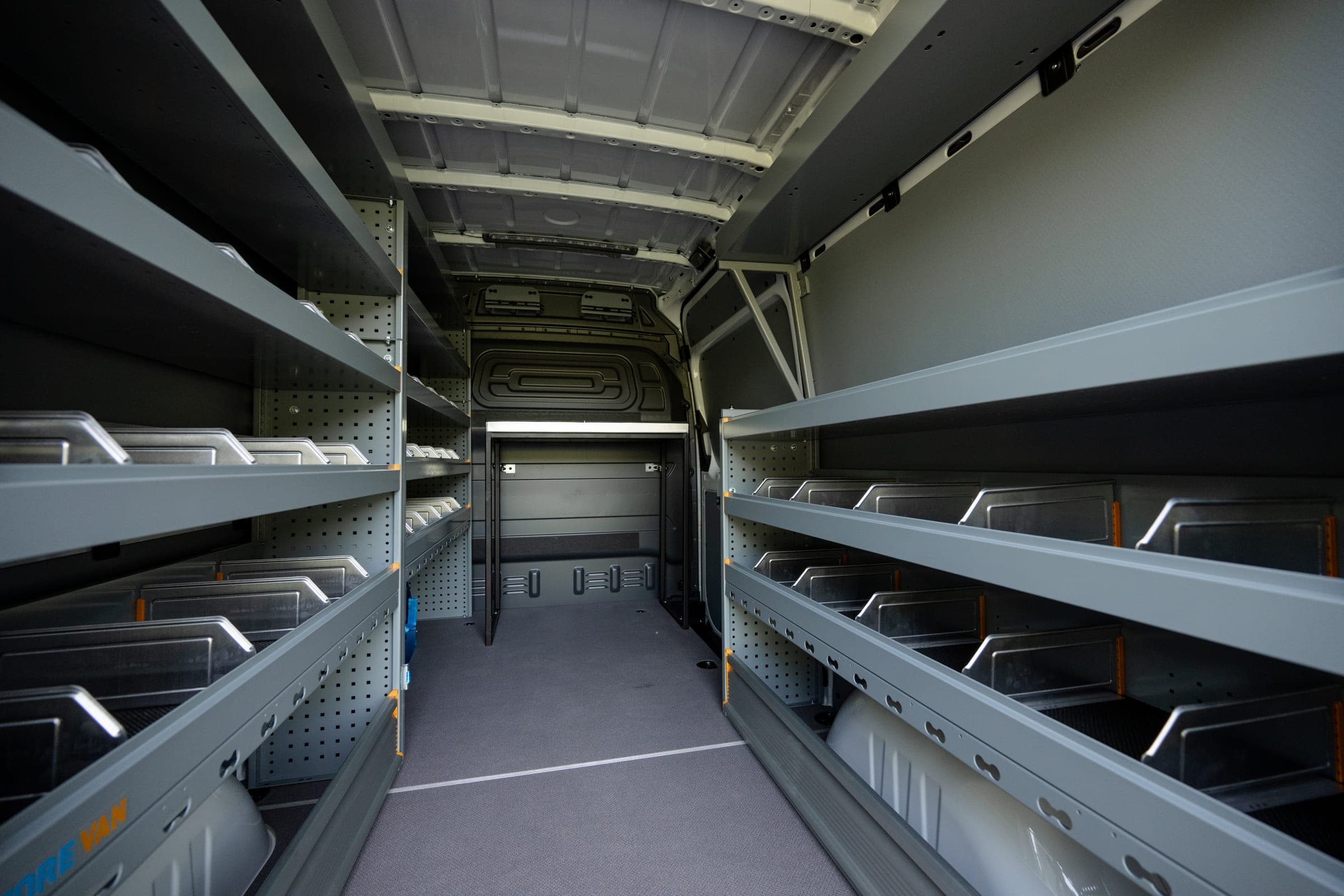 Intérieur de fourgon aménagé, longues étagères en aluminium sur toute la longueur de la zone de chargement