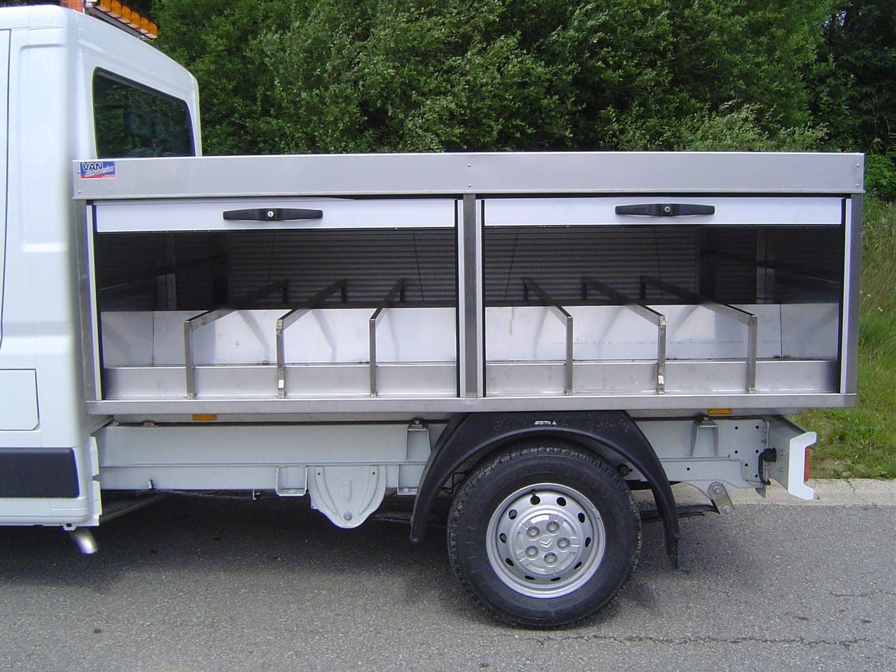 Caisse à volets roulants en aluminium sur châssis-cabine blanc, compartiments à casiers ouverts
