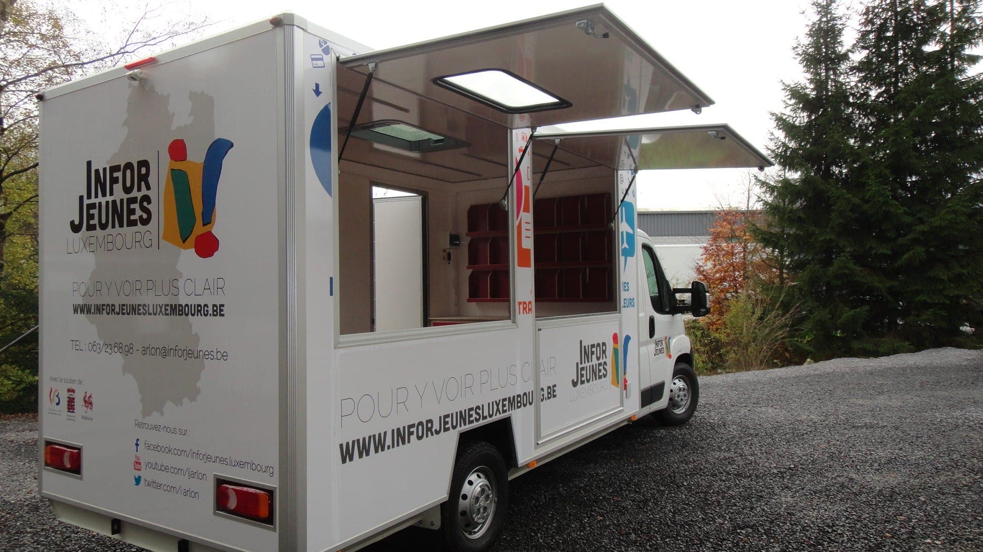 Bureau mobile d’un service d’information jeunesse, auvents relevés et comptoir ouvert sur l’extérieur