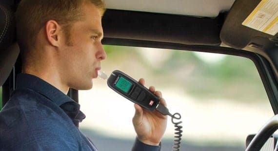 Conducteur soufflant dans un éthylotest portatif relié par un cordon spiralé, au volant d’un utilitaire