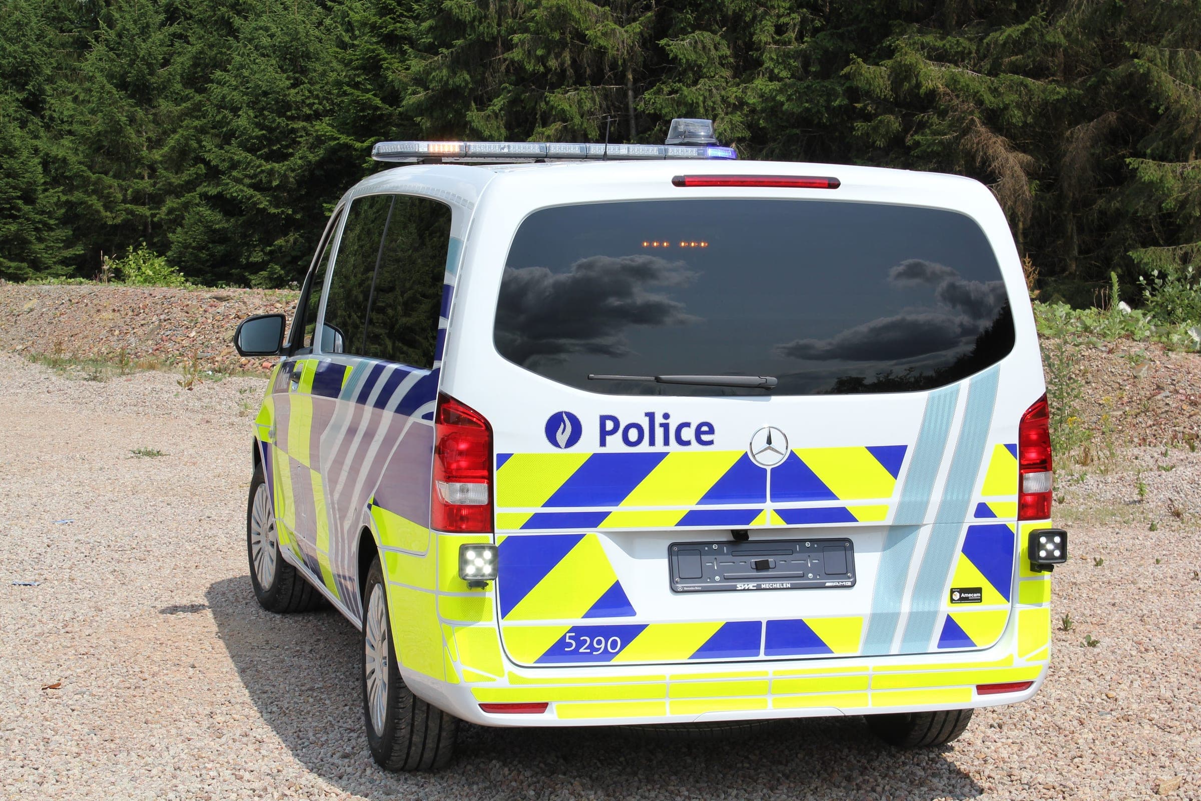 Mercedes Vito de police en livrée jaune et bleue rétroréfléchissante, vu de trois quarts arrière