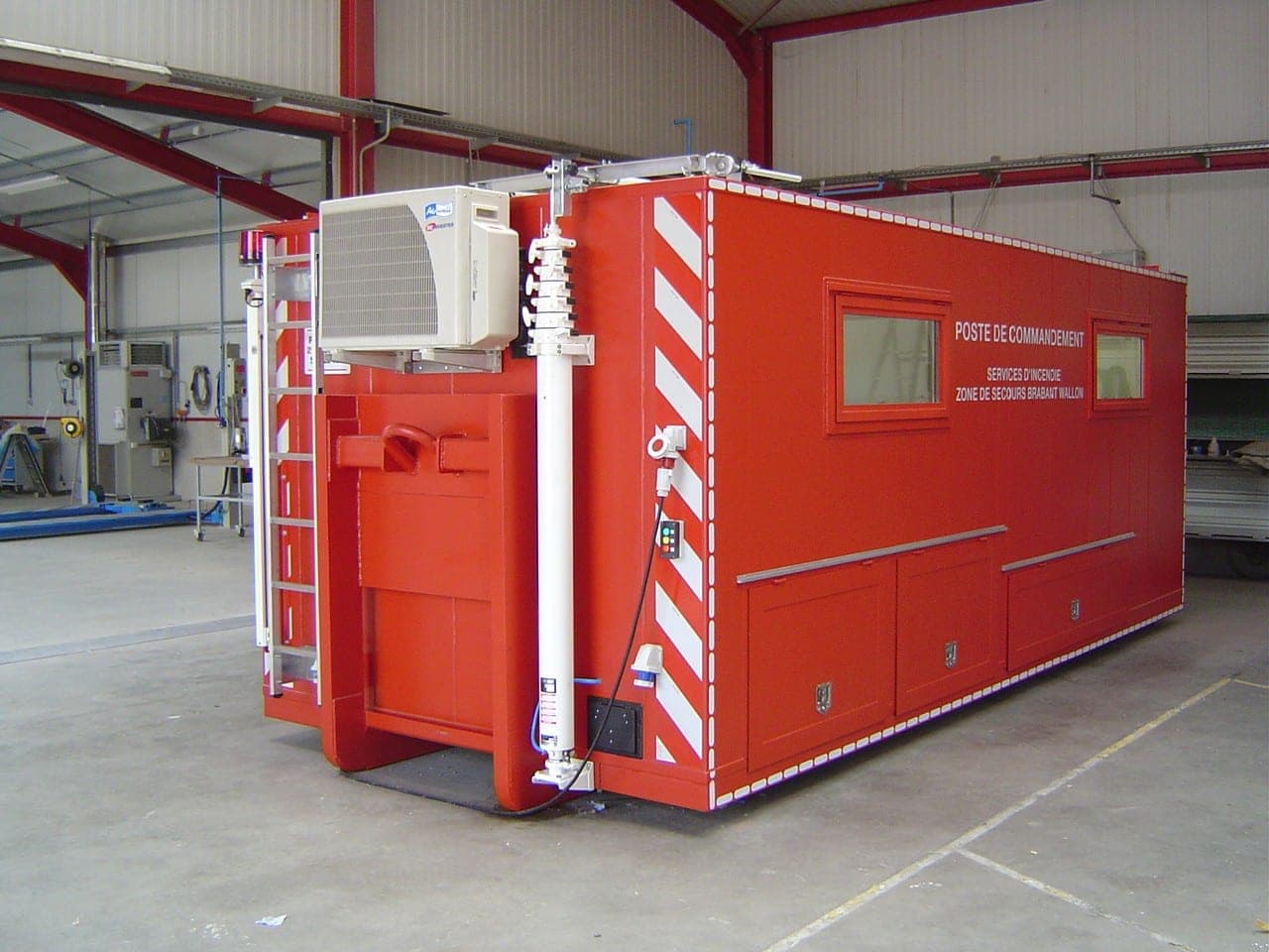 Poste de commandement mobile rouge sur remorque, équipé d’un climatiseur, d’un mât et de bandes rétroréfléchissantes