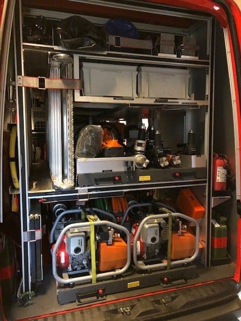 Rayonnage arrière d’un véhicule de pompiers, deux motopompes sur le plancher, bacs de rangement, tuyaux et extincteurs