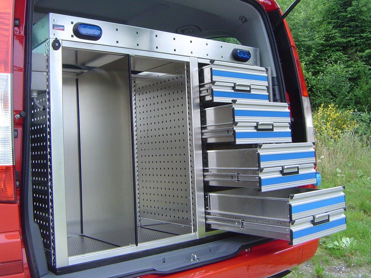 Coffre d’un véhicule de pompiers avec tiroirs aluminium coulissants sortis et compartiment vertical de rangement