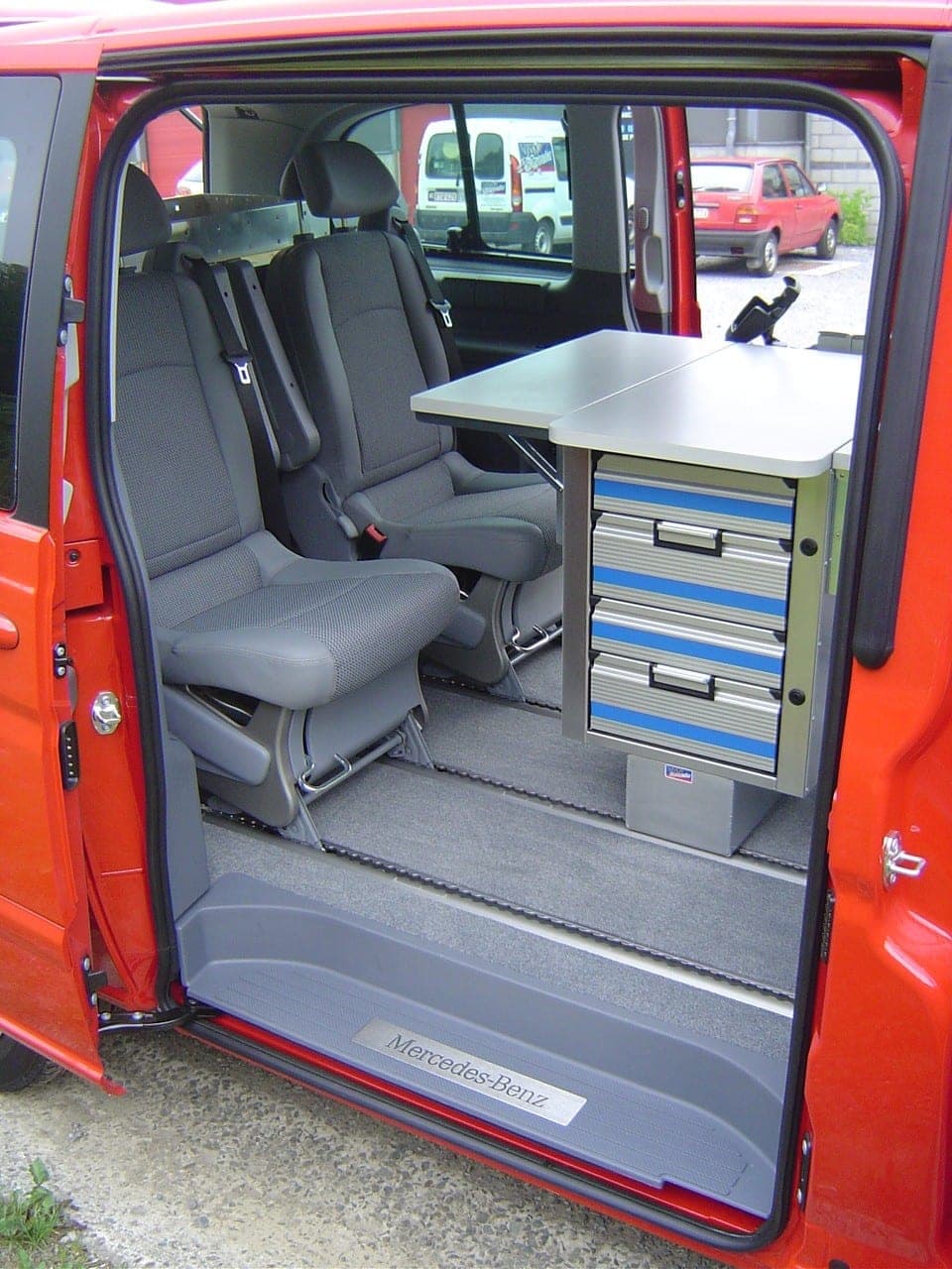 Intérieur d’un Vito de pompiers : table escamotable, caisson à tiroirs bleus et sièges de transport
