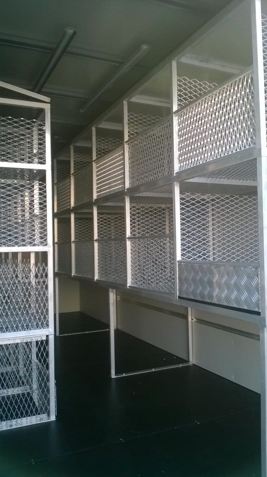 Rayonnage aluminium à fonds grillagés installé sur toute la longueur d’une caisse aménagée