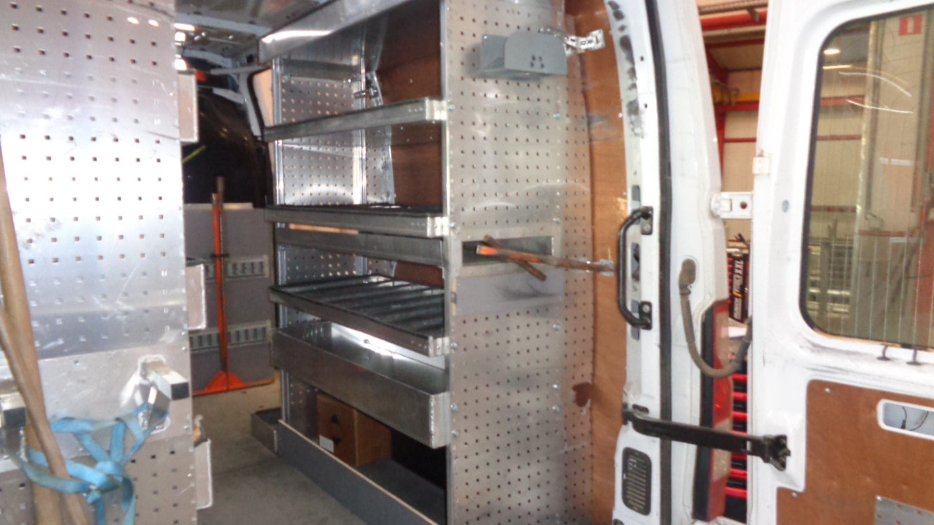 Rayonnage aluminium à étagères et panneaux perforés installé dans un fourgon aux portes ouvertes
