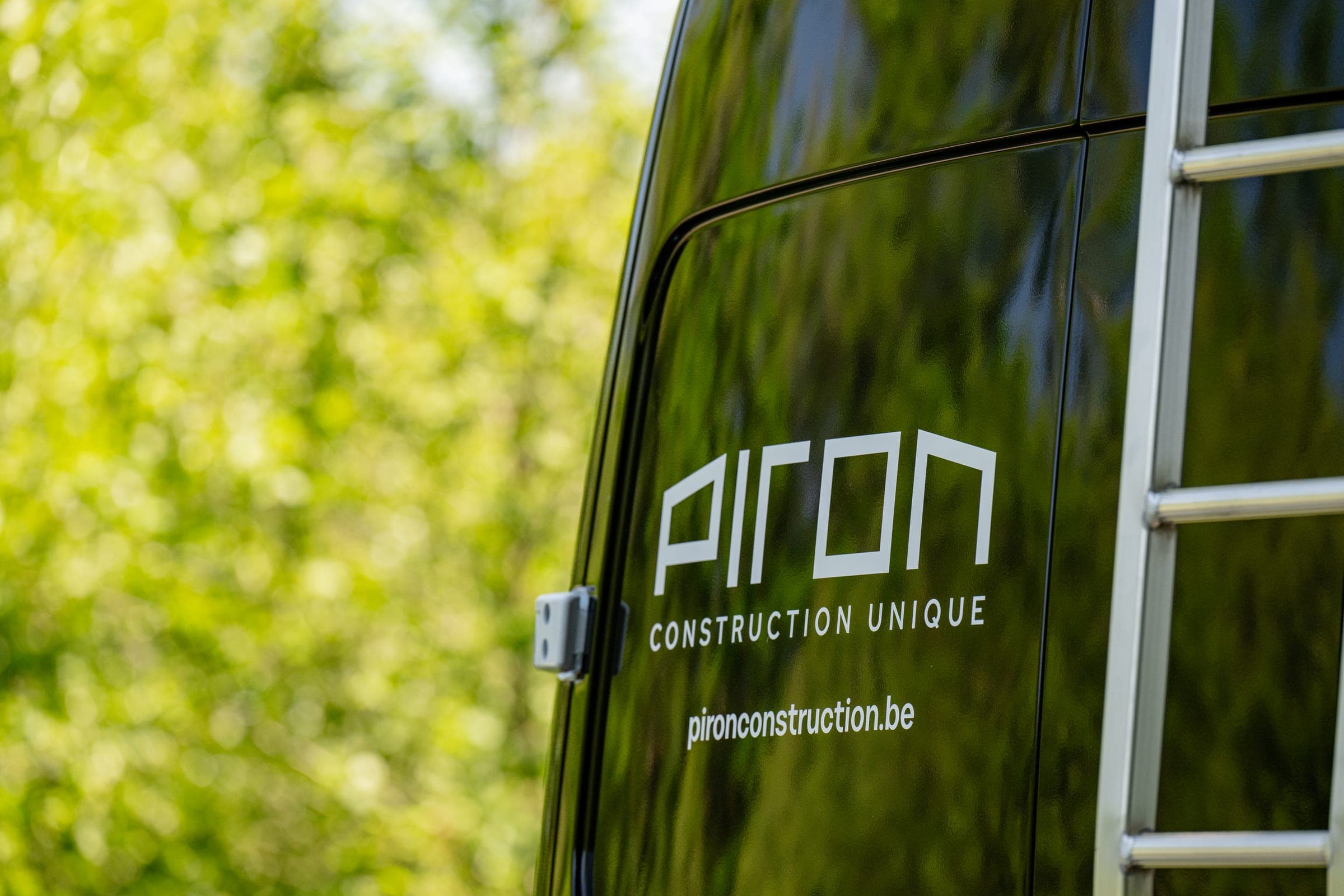 Détail du lettrage Piron Construction Unique sur la porte arrière d’un fourgon noir