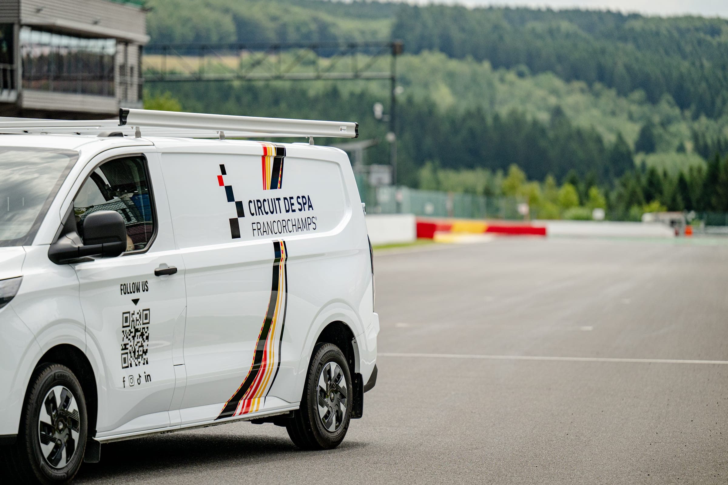 Ford Transit Custom lettré aux couleurs du circuit de Spa-Francorchamps, vu de profil sur la piste